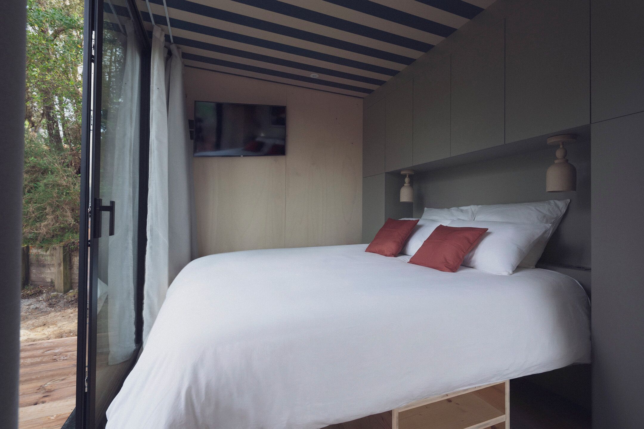 Ein Schlafzimmer mit einem Bett, einem Fenster und einer Decke mit horizontalen Linien.