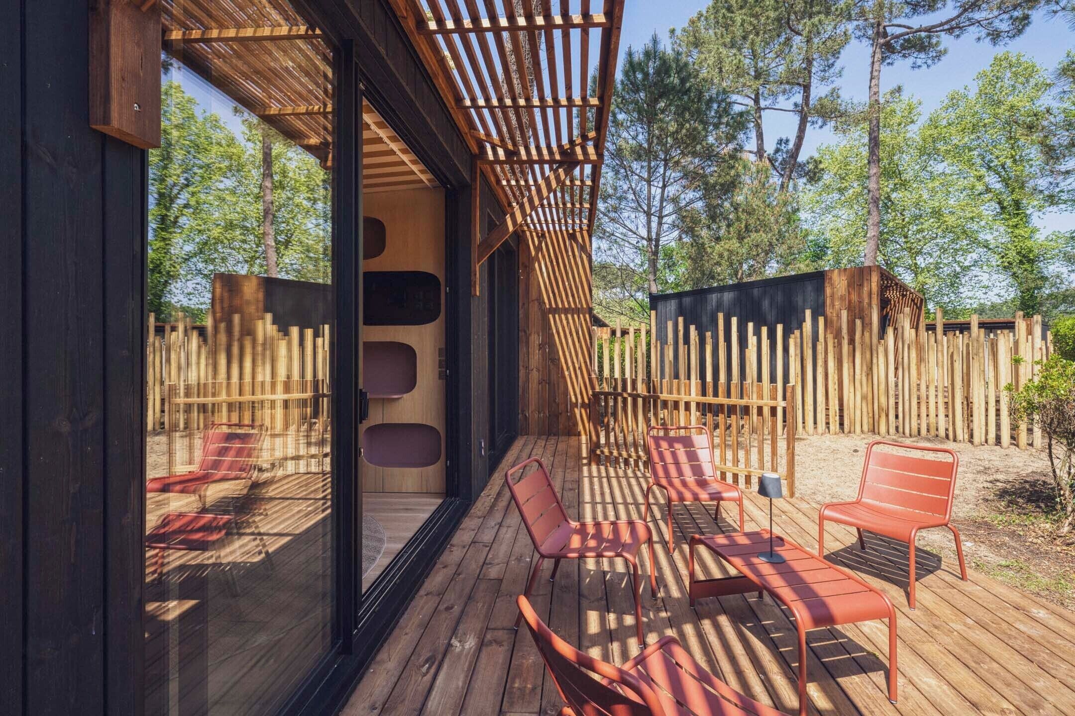A wooden deck with outdoor seating, a pergola, and a view of the surrounding forest.