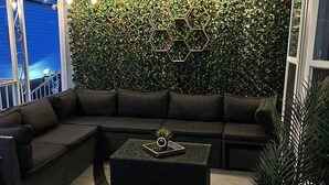 Ein modernes Wohnzimmer mit einem Ecksofa, einem Couchtisch und einer Wand, die mit Grünpflanzen und sechseckigen Lampen dekoriert ist.
