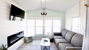 Ein Wohnzimmer mit Kamin, einer Couch, einem Couchtisch und einem an der Wand befestigten Fernseher.