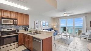 A modern kitchen with a central island, a dining area with a view, and a balcony overlooking the ocean.