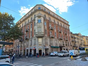 A multi-story building with a classic architectural style, featuring ornate balconies and a ground-floor entrance with signage for a cafe and a bakery. - Dorolea Rooms Torino Centro (Turin)
