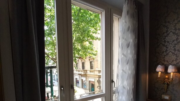 A room with a large window, a marble floor, and a small table with a lamp. - Dorolea Rooms Torino Centro (Turin)