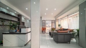 A modern kitchen with a marble countertop and a central island, a living area with a grey sofa and a coffee table, and a large window with sheer curtains. - Huangguoshu Guchunxiang Homestay (Zhenning)