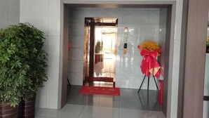 Entrada de hotel con una planta en maceta, alfombra roja y un lazo decorativo.