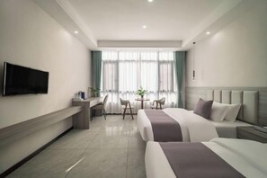 A modern hotel room with a flat-screen TV, a desk with a chair, a round table with chairs, and two beds with headboards. - Huangguoshu Guchunxiang Homestay (Zhenning)