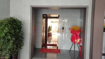 An entrance with a red mat, a potted plant, and a red and yellow floral arrangement.