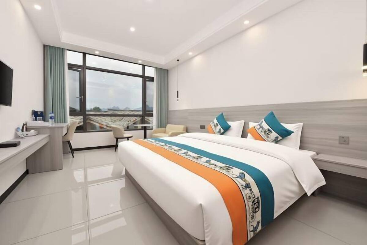 A modern hotel room with a large bed, a desk, and a chair.