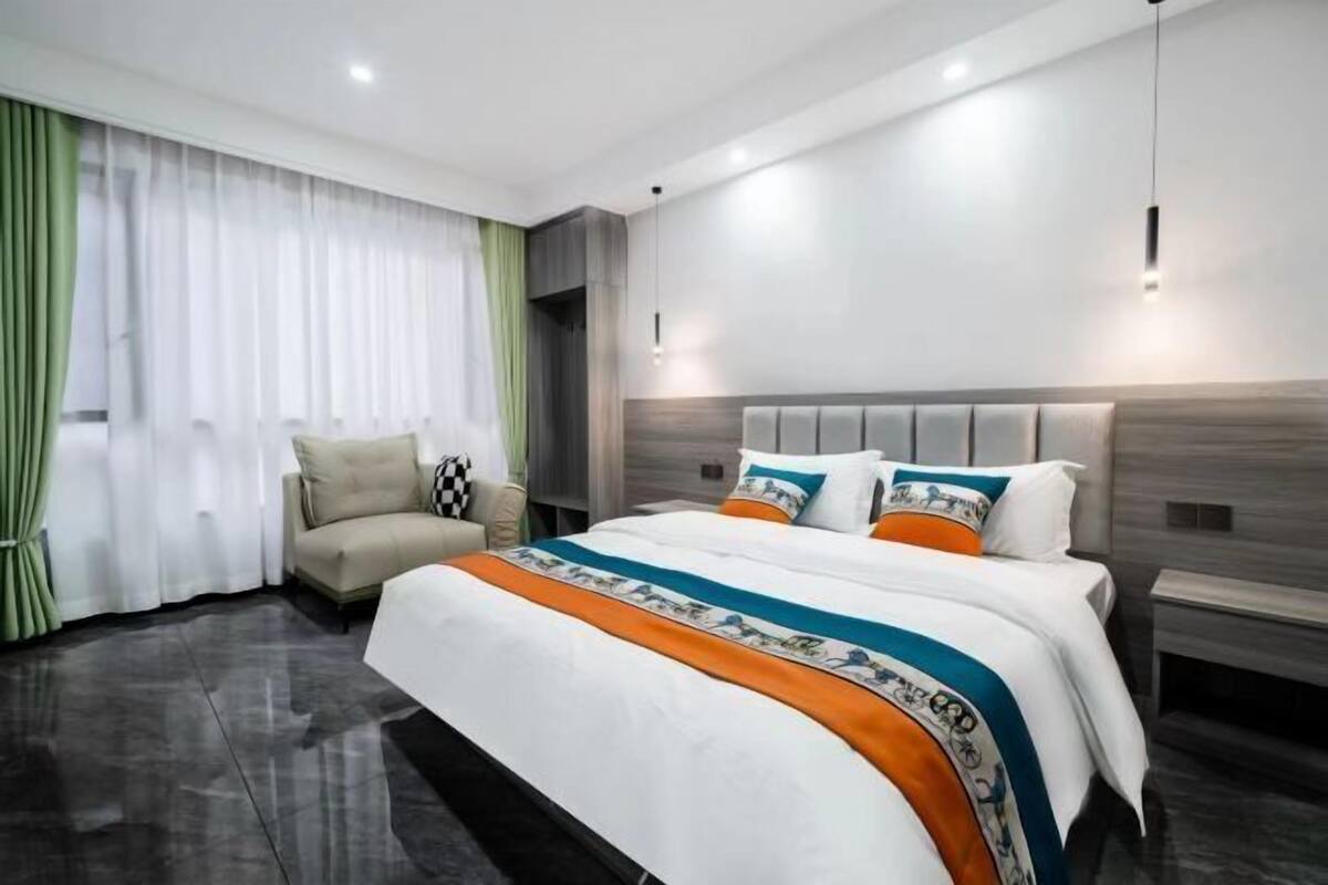 A modern hotel room with a large bed, a sofa, and a view of the city.