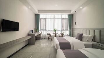 Una habitación de hotel con cama, escritorio, silla, televisor y ventana con cortinas.