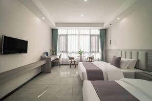 A hotel room with a bed, a desk, a chair, a TV, and a window with curtains. - Huangguoshu Guchunxiang Homestay (Zhenning)