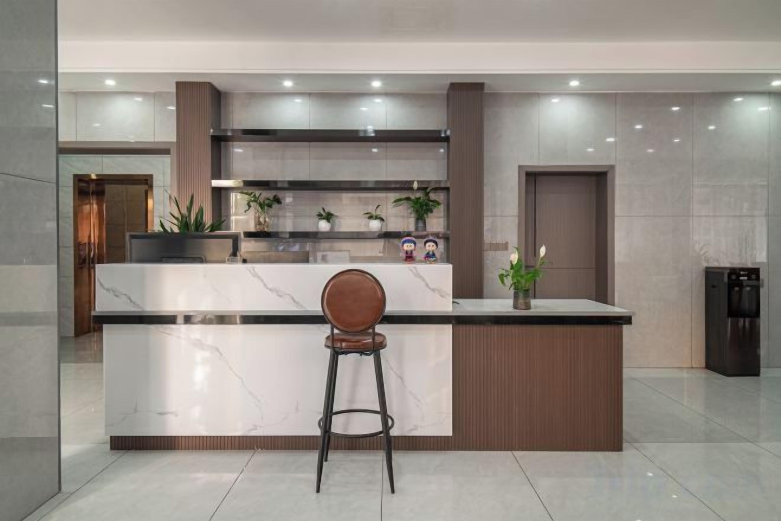 A modern kitchen with a marble countertop, a wooden bar stool, and a built-in oven.