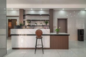 A modern kitchen with a marble countertop, a wooden bar stool, and a built-in oven. - Huangguoshu Guchunxiang Homestay (Zhenning)