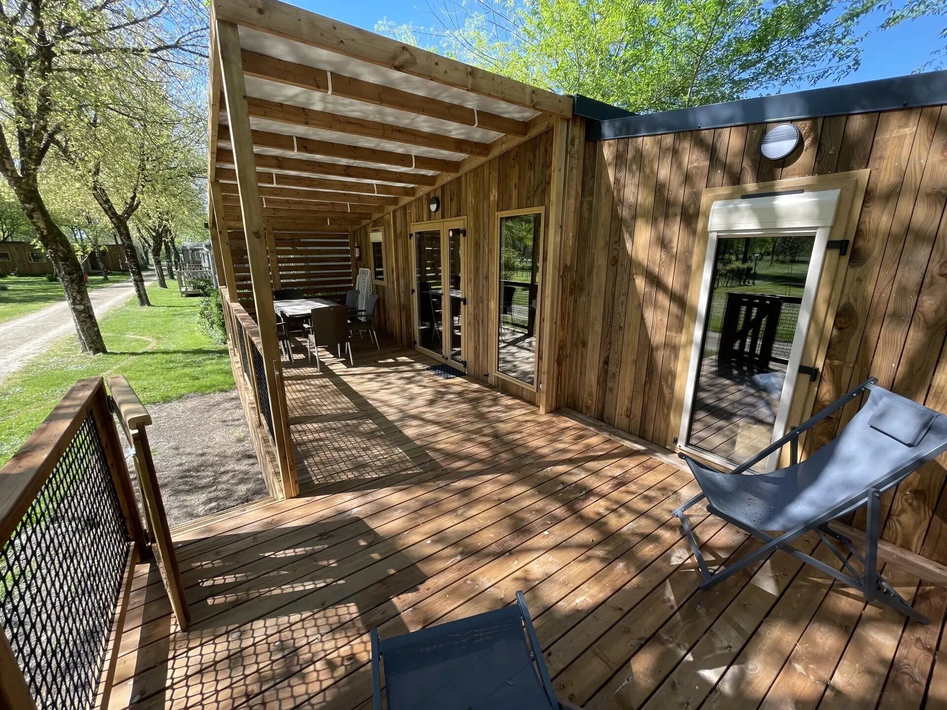 Un patio in legno con zona salotto coperta, una porta e una finestra.