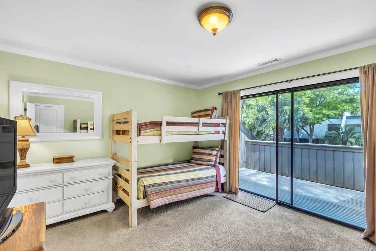 Ein Zimmer mit Etagenbetten, einem weißen Schminktisch, einem Fernseher und einem Balkon mit Blick.