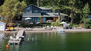 Ein modernes Haus mit einer Anlegestelle und Booten, umgeben von Bäumen.