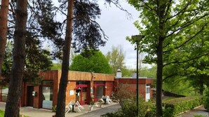 A rustic building with a red door and a small outdoor seating area with white chairs. - ZEcamping 3* locatif TV 34m2 2 pers (Vorey)