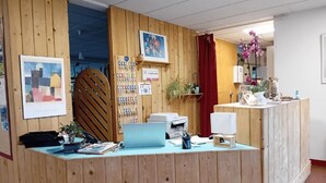 A reception desk with a laptop, printer, and various office supplies. There are framed artworks and a plant on the wall. - ZEcamping 3* locatif TV 34m2 2 pers (Vorey)