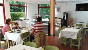 A restaurant with tables set for dining, a coffee machine, and a television on the wall. - ZEcamping 3* locatif TV 34m2 2 pers (Vorey)
