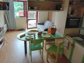 Un comedor con una mesa preparada para dos, un sofá y una zona de cocina con microondas.