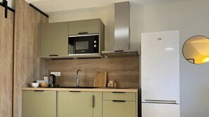 Une cuisine moderne équipée d’un four à micro-ondes encastré, d’une hotte en acier inoxydable et d’un réfrigérateur blanc.