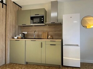 A modern kitchen with a built-in microwave, a stainless steel range hood, and a white refrigerator.