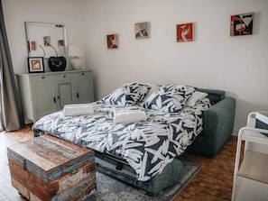 A bedroom with a bed, a dresser, a mirror, and artwork on the wall.