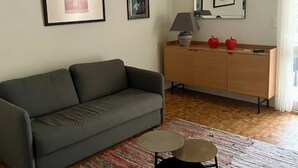 Un salon avec un canapé gris, un meuble en bois et une petite table ronde.