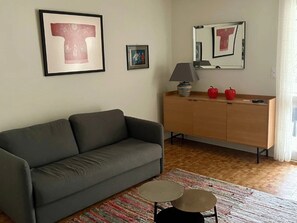 A living room with a grey sofa, a wooden cabinet, and a small round table.