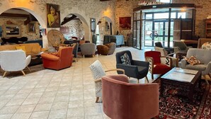 A spacious lobby with a mix of modern and rustic decor, featuring a variety of seating options and a large glass door leading outside. - ZEcamping 3 étoiles piscine cottage TV LV 42m2 6 pers (Vouvant)