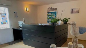 A reception desk with a 'Welcome' sign, a plant, and a decorative bird sculpture.