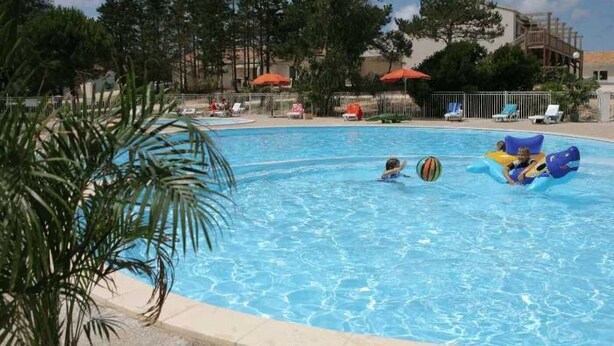 A swimming pool with clear blue water, surrounded by lounge chairs and umbrellas.