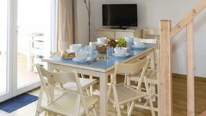 Un comedor con una mesa lista para cuatro, sillas, un televisor y una escalera.