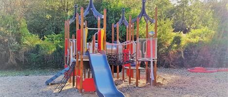 A playground with a slide, climbing structures, and a swing set.