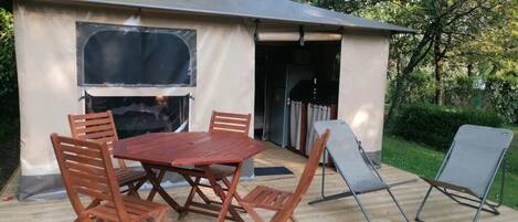 Un espacio al aire libre techado con una mesa y sillas de madera, una parrilla y una silla plegable.