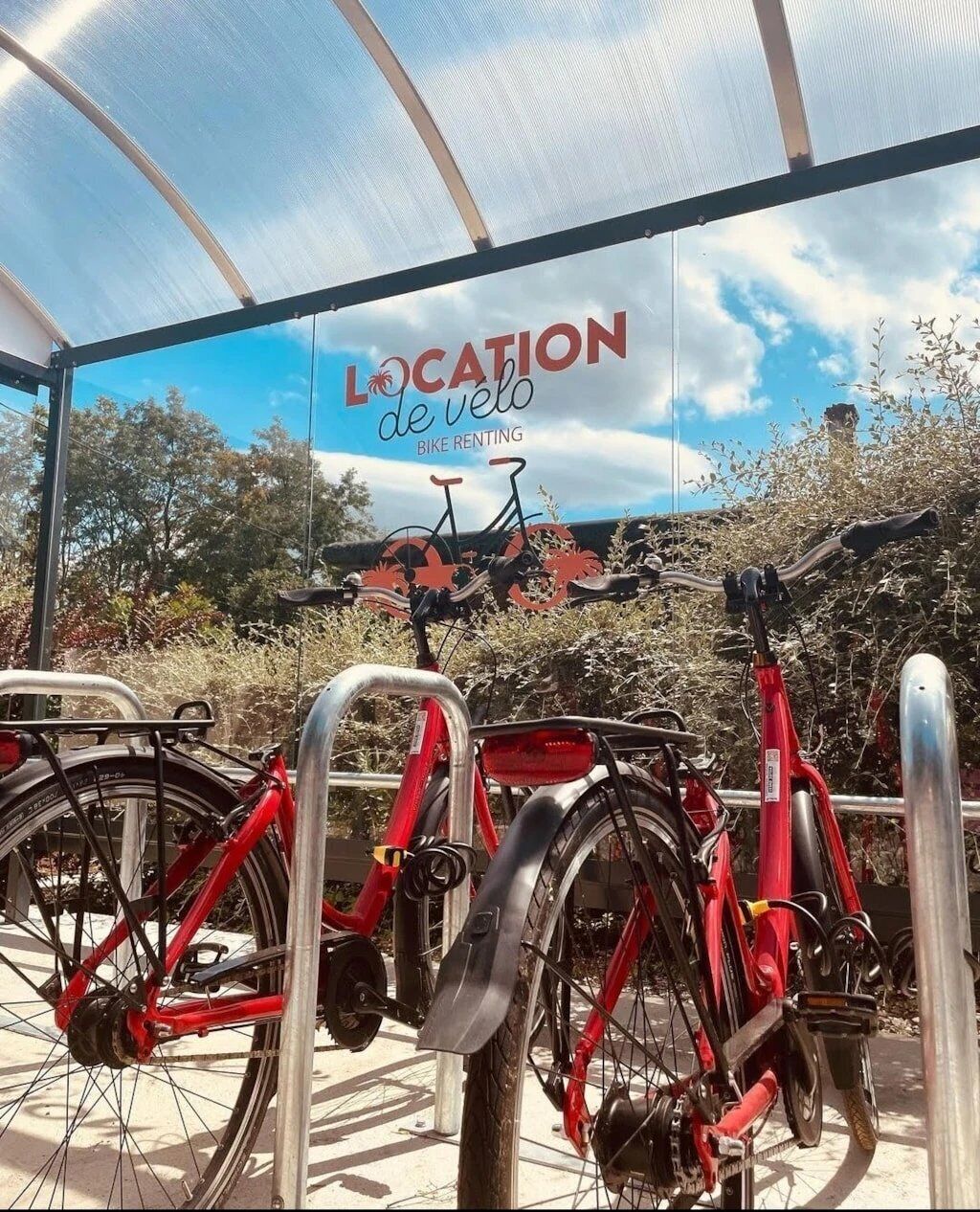A bike rental station with a clear sky and trees in the background.