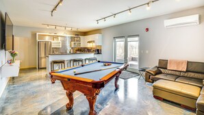 A modern living room with a pool table, a sofa, and a kitchen area in the background. - Home Near Road America & Elkhart Lake (Elkhart Lake)