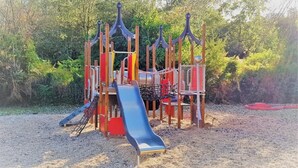 Un parque infantil con tobogán, estructuras para escalar y columpios.