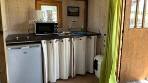 Pieni, käytännöllinen keittiö, jonka seinät ovat puuta, ja jossa on mikroaaltouuni, kahvinkeitin ja pesuallas.