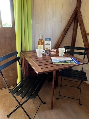 A wooden table with two white cups, a bottle, and a box of cereal.