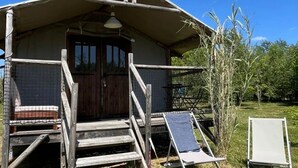 Tunnelmallinen, maalaishenkinen mökki, jossa on puinen portaikko, joka johtaa ovelle, pieni kuisti ja aurinkopaneeli.