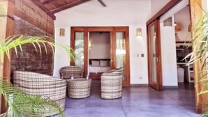A room with a bed, a wooden door, and wicker furniture. - Private House! 2' to the beach, AC, Wi-Fi, Pool (Malpais)