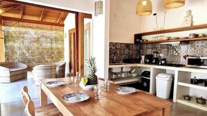 A modern kitchen with a wooden dining table set for four, a fruit bowl, and a patterned backsplash. - Private House! 2' to the beach, AC, Wi-Fi, Pool (Malpais)