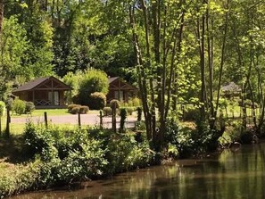 A serene lakeside setting with a wooden cabin and a gazebo.