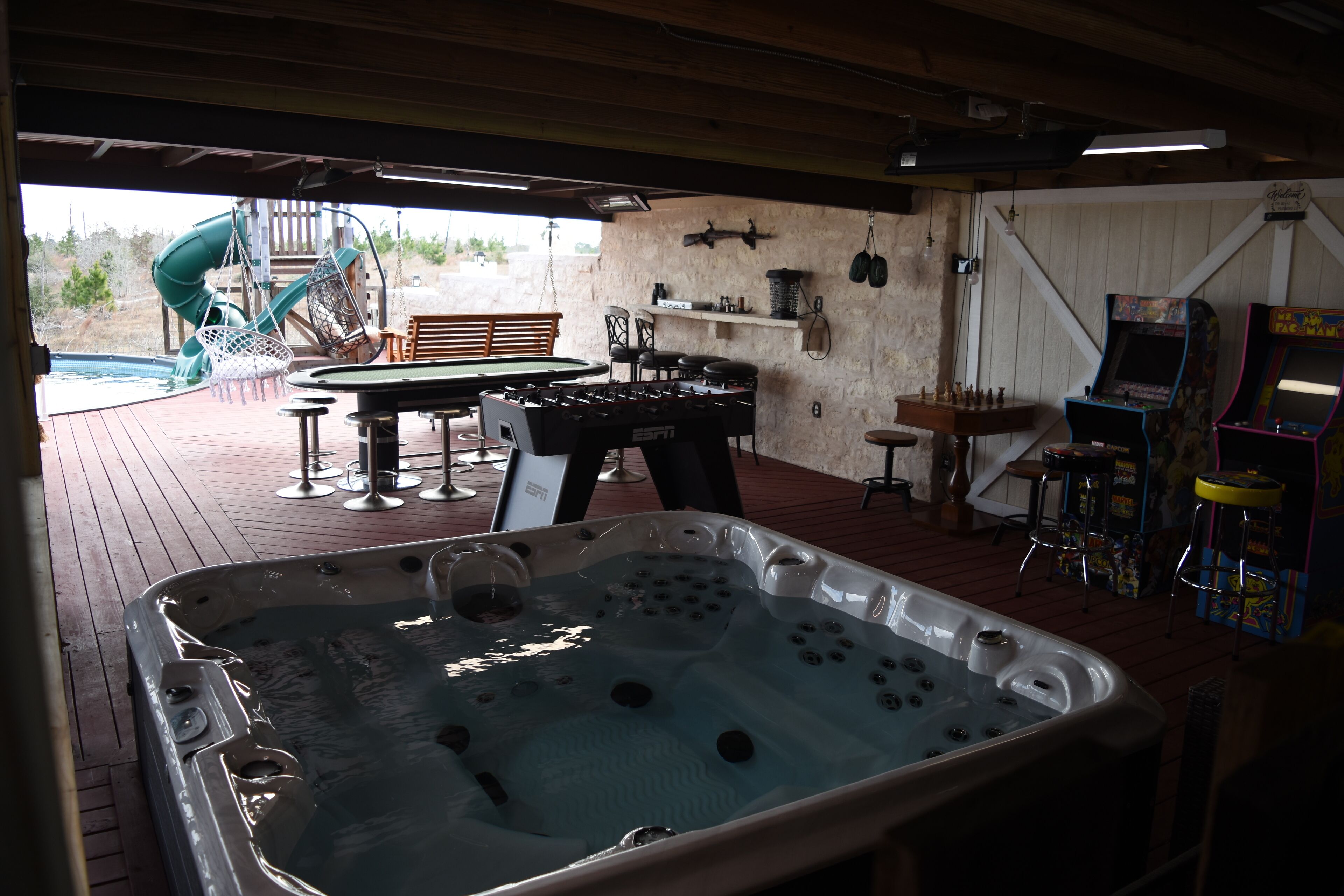 Ein Whirlpool, Sitzgelegenheiten im Freien und Spielautomaten in einem überdachten Bereich.