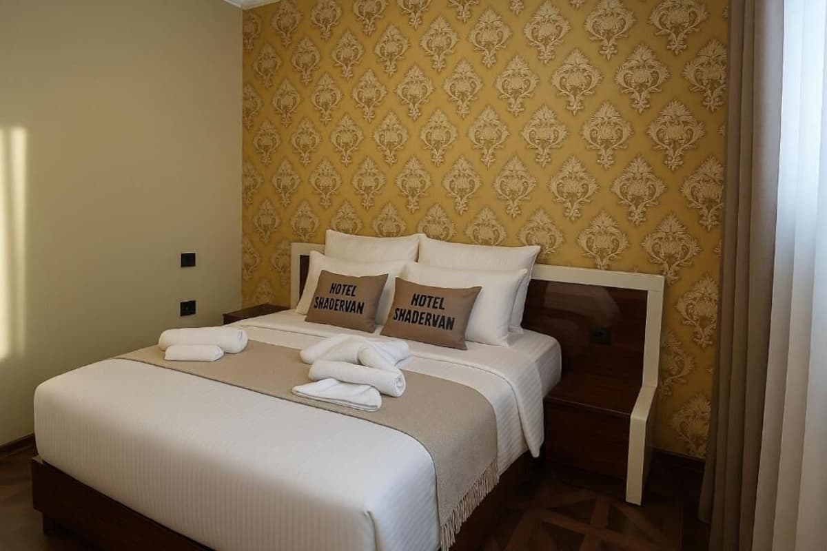 A hotel room with a bed, pillows, and a blanket.