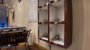 A hotel room with a wooden cabinet with numbered compartments, a desk with a chair, and a wall-mounted air conditioning unit. - Hotel Shadervan (Prizren)