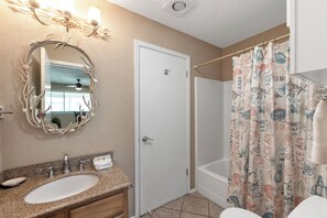 A bathroom with a sink, mirror, and shower curtain.