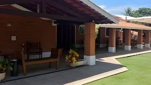 Un edificio con un patio techado, una banca y plantas en macetas.