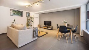 Ein modernes Wohnzimmer mit einer Couch, Fernseher, Esstisch und Stühlen.